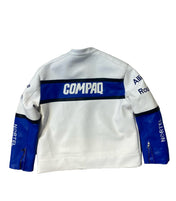 White sweatshirt with blue accents and visible branding on a textured stone wall.