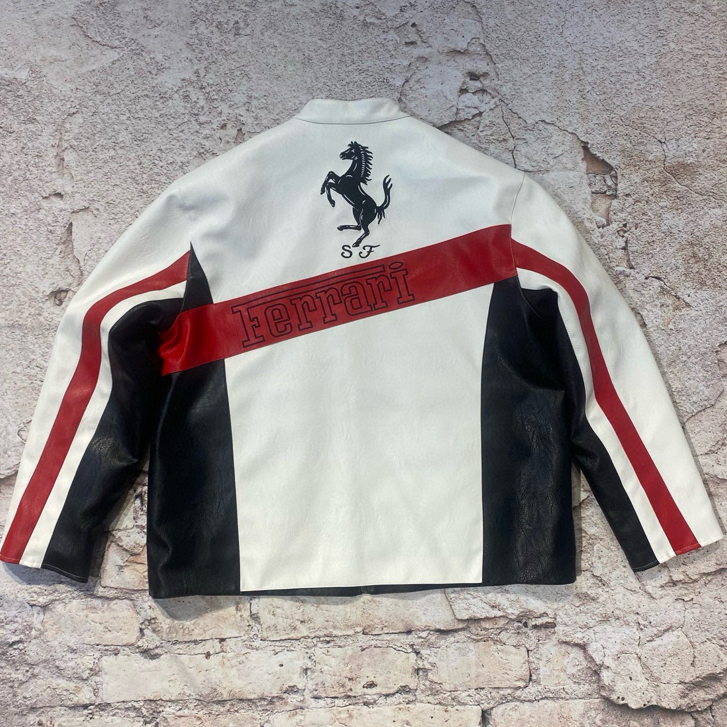 White jacket with black and red accents featuring a horse logo on a textured surface
