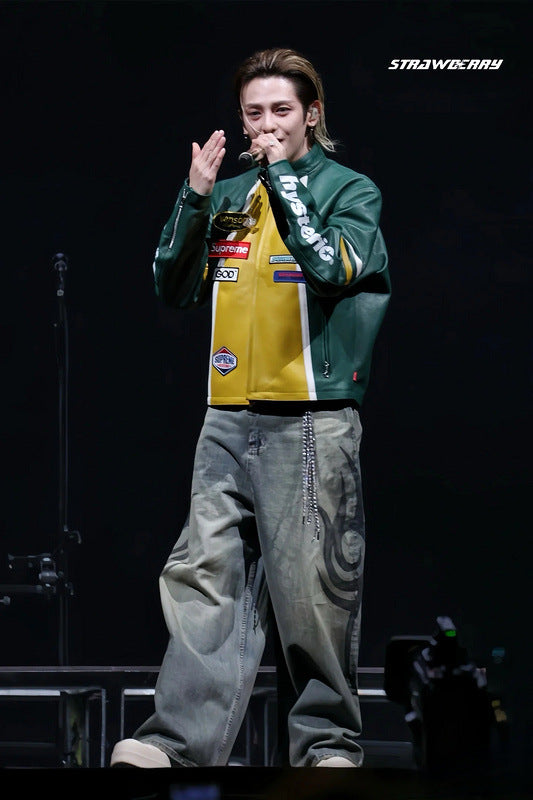 Person on stage wearing a colorful jacket and gray pants, with 'Strawberry' logo in the corner.