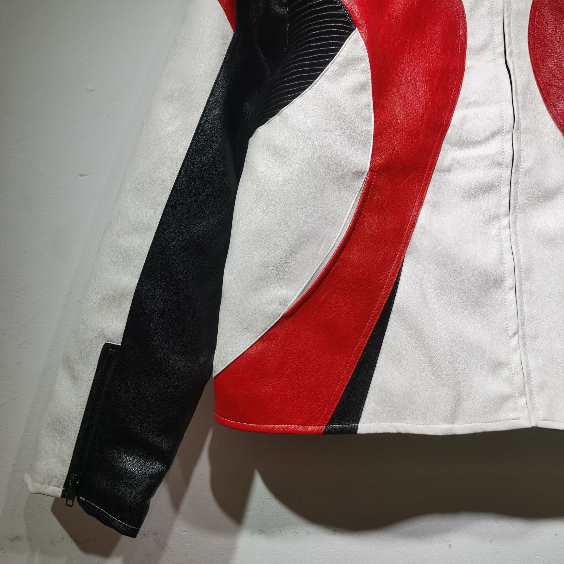 Close-up of a leather jacket with black, red, and white color pattern on a plain background