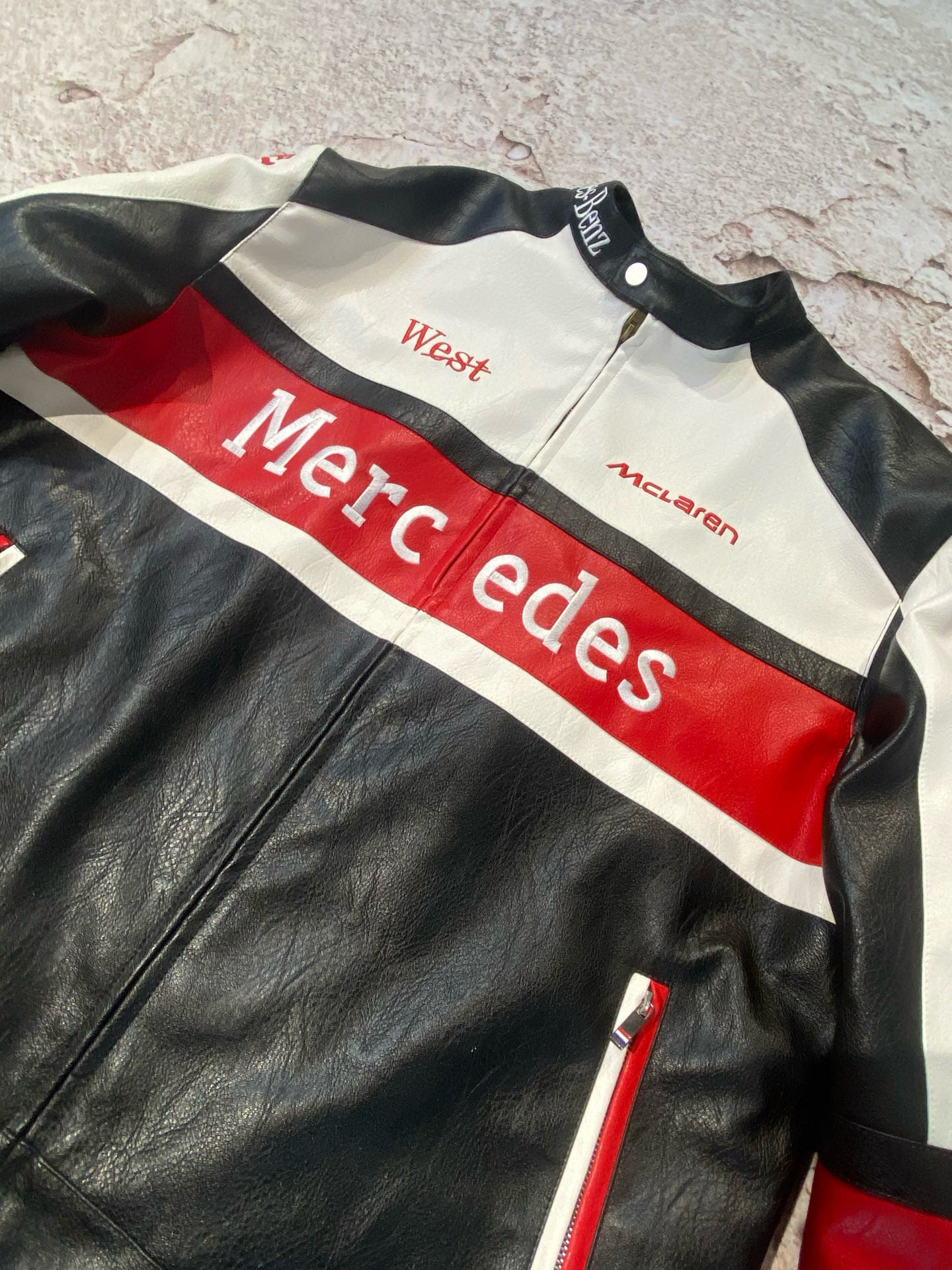 Black leather jacket with red and white accents featuring Mercedes branding.