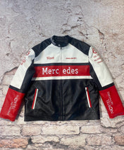 Black, white, and red racing jacket with Mercedes branding on a textured stone background