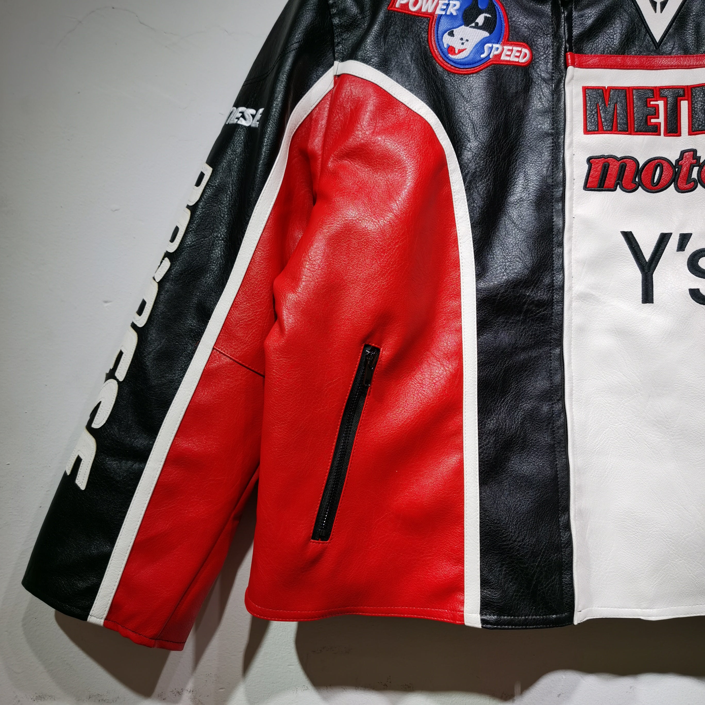 Close-up of a leather jacket with visible branding and logos on a plain background