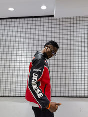 Person wearing a red and black jacket with 'Diesel' branding against a grid-patterned wall.