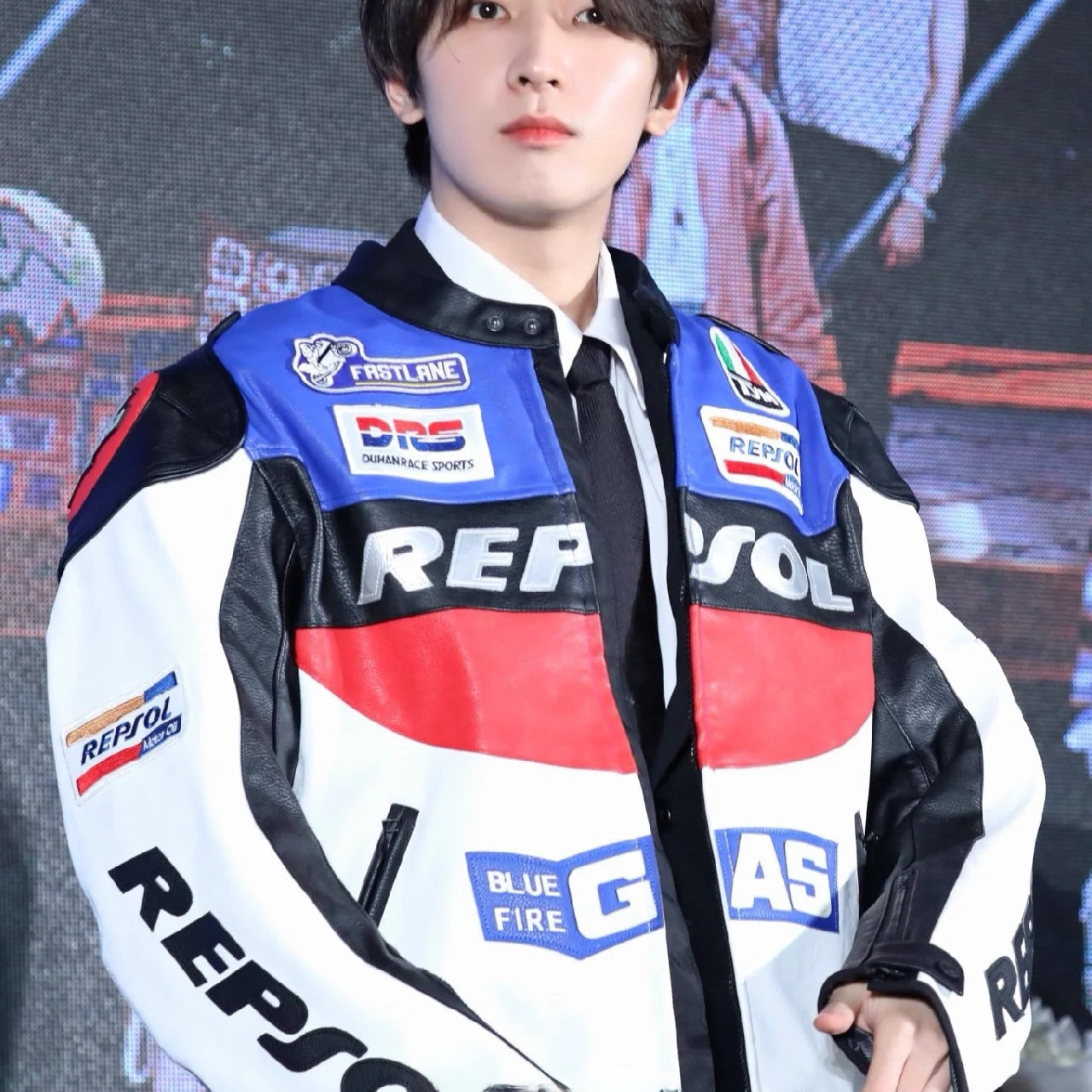 Person wearing a Repsol jacket with logos in a studio setting