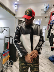 Person wearing a black and white jacket with a red and green cap in a store setting.