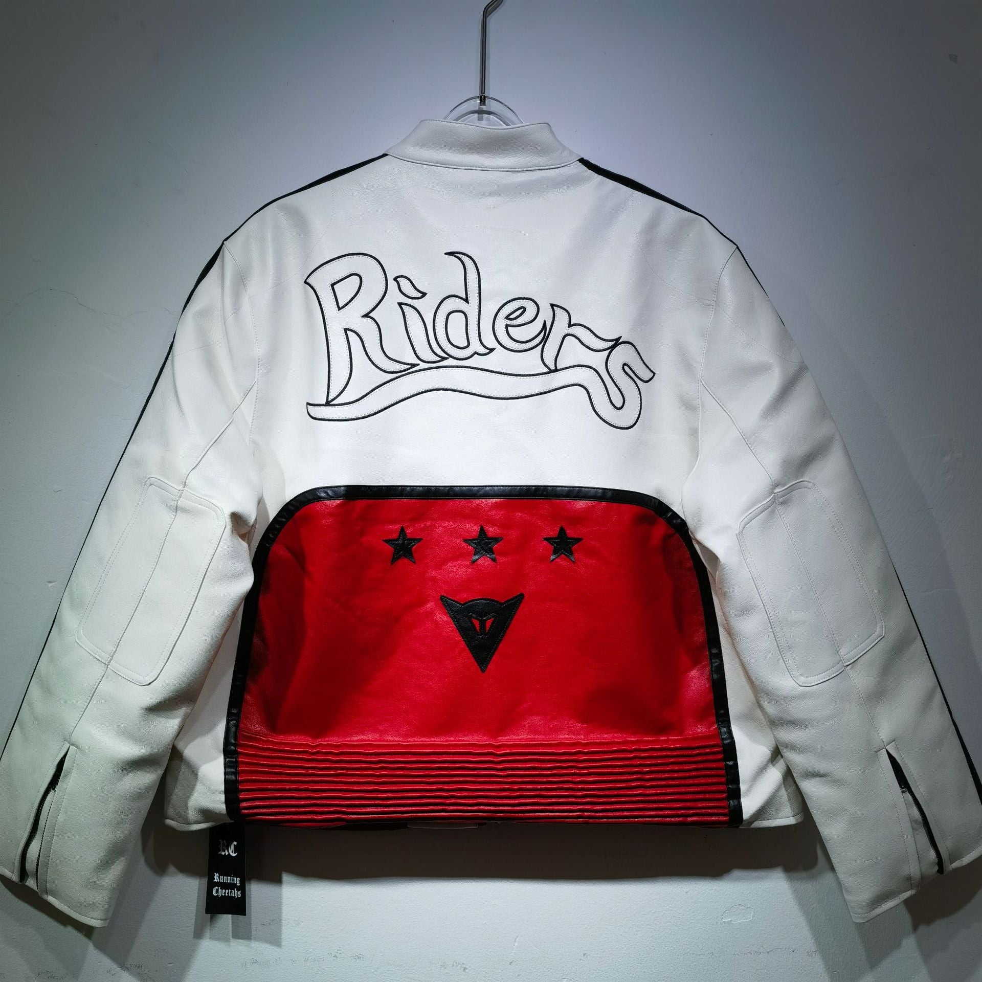 White jacket with red back panel and 'Riders' logo on a gray background