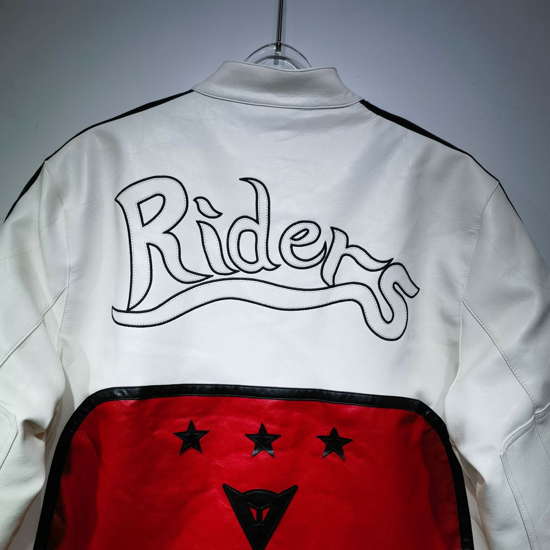 White jacket with 'Riders' logo on a gray background