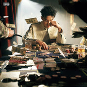 Person at a poker table with money and drinks, with a blurred background
